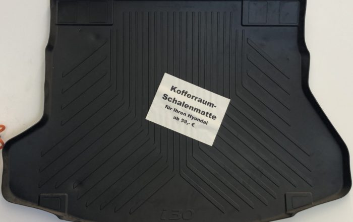 Schwarze Kofferraummatte mit hohem Rand, mit weißem Etikett „Kofferraum-Schalenmatte“.