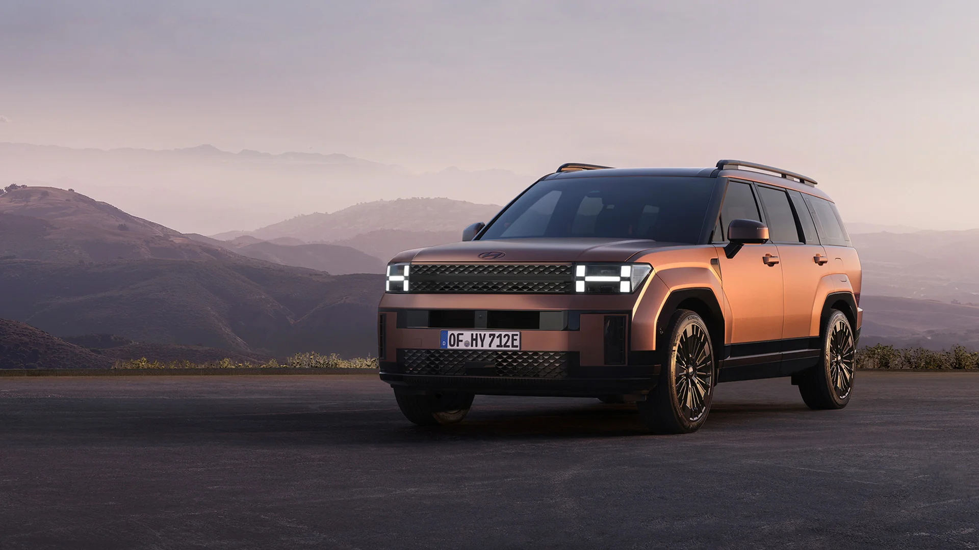 Hyundai SANTA FE steht vor bergiger Landschaft bei Sonnenuntergang, betont das prämiertes Design