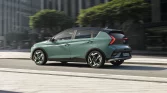 Modern green and black Hyundai BAYON hatchback with sporty wheels in urban cityscape.