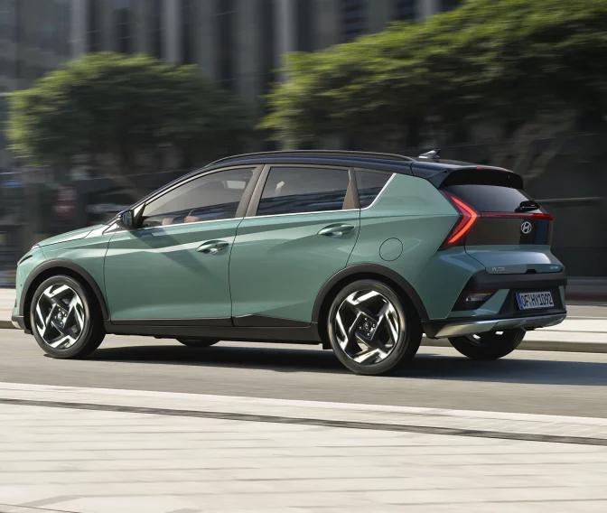 Modern green and black Hyundai BAYON hatchback with sporty wheels in urban cityscape.