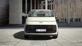 Modern compact city car with sleek design and urban architecture backdrop.
