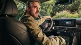 Mann im grünen Jacke fährt schwarzen Hyundai SUV, Innenraum mit roter Naht, grüne Landschaft draußen sichtbar