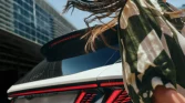 Weißer Hyundai SUV von hinten vor modernem Glasgebäude, Frau mit wehenden Haaren in urbaner Umgebung