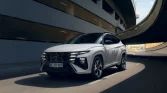 Weißer Hyundai SUV fährt dynamisch auf urbaner mehrstöckiger Straßenbrücke mit moderner Architektur