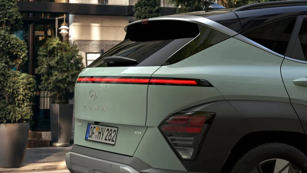 Hybrider grüner Hyundai SUV von hinten in urbaner Umgebung mit Pflanzen und modernem Gebäude