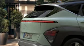 Hybrider grüner Hyundai SUV von hinten in urbaner Umgebung mit Pflanzen und modernem Gebäude