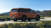 Oranger Hyundai SUV von hinten auf Offroad-Pfad in hügeliger Naturlandschaft bei klarem Himmel