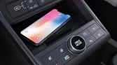 Innenraum eines modernen grauen Hyundai SUV mit Smartphone auf kabelloser Ladestation im Fokus