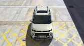 Beige Hyundai Kleinwagen von oben auf Parkfläche mit gelben Markierungen, urbaner Hintergrund