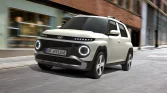 Weißer Hyundai kompakter SUV fährt in urbaner Straße mit modernen Gebäuden im Hintergrund