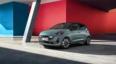 Blau-grüner Hyundai Kompaktwagen in 3/4-Frontansicht vor bunten, modernen Stadtwänden geparkt