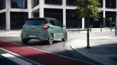 Grüner Hyundai Kleinwagen von hinten auf moderner Stadtstraße mit Gebäude und Baum bei Sonnenschein