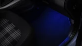 Innenraum eines Hyundai Kleinwagens mit blau beleuchtetem Fußraum und kariertem Sitzbezug, Nahaufnahme