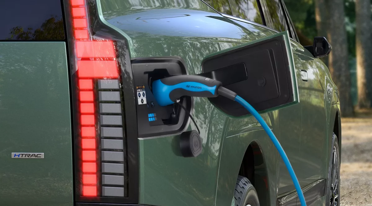 Grüner Hyundai Elektro-SUV beim Laden von hinten in natürlicher Parkumgebung, Nahaufnahme Ladeanschluss und Rücklicht