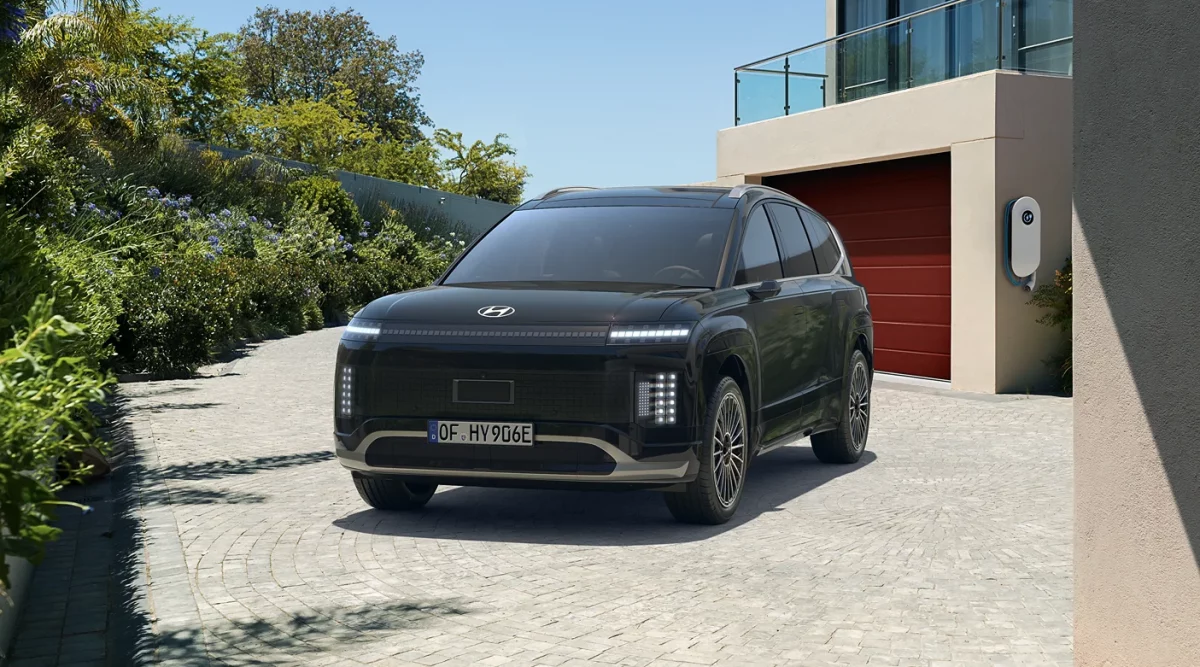 Schwarzer Hyundai SUV seitlich auf gepflasterter Einfahrt vor modernem Haus mit Ladestation geparkt
