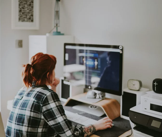 Frau mit Pferdeschwanz arbeitet konzentriert an Computer in modern eingerichteter Heimarbeitsplatzumgebung.