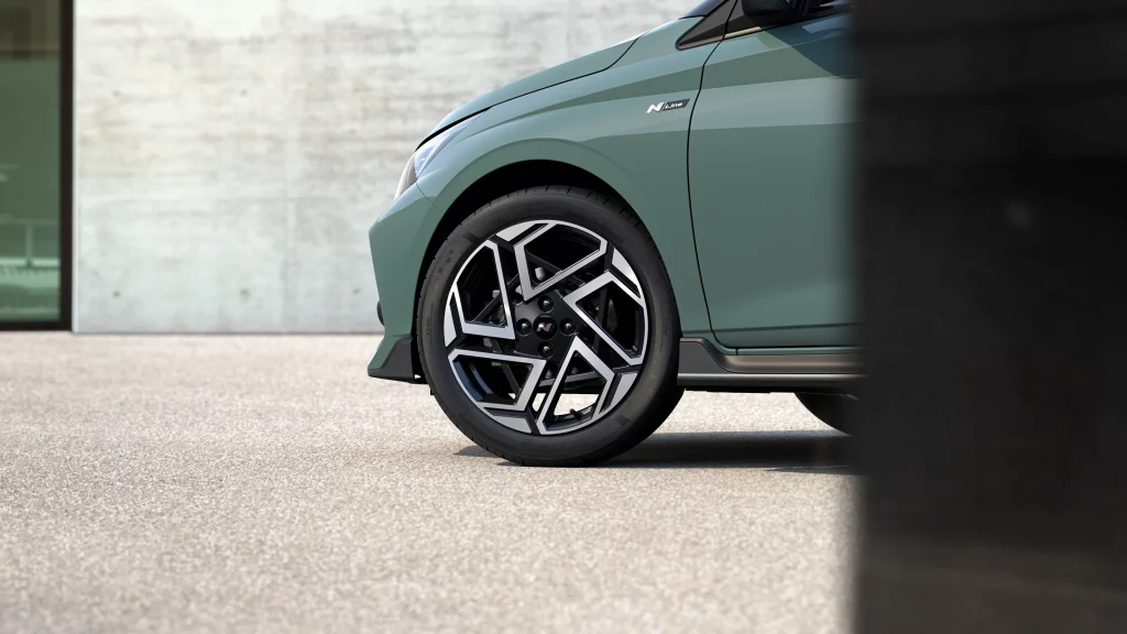 Sportlicher grüner Hyundai Kompaktwagen, Nahaufnahme Rad und Kotflügel, moderne urbane Kulisse