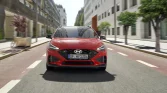 Roter Hyundai Kompaktwagen frontal fahrend auf moderner Stadtautobahn mit Gebäuden und Bäumen im Hintergrund
