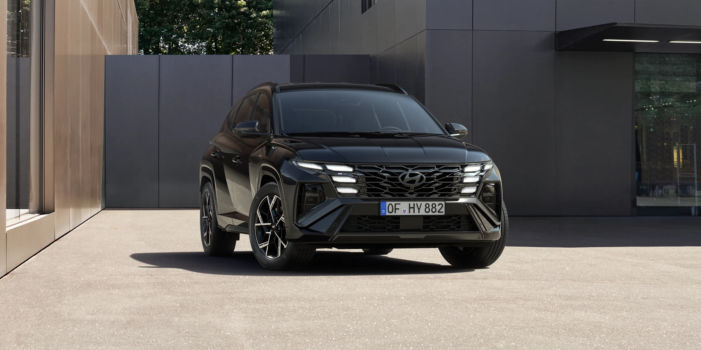 Black month 6 Schwarzer Hyundai SUV frontal vor modernem urbanem Hintergrund mit Gebäuden und leichter Begrünung