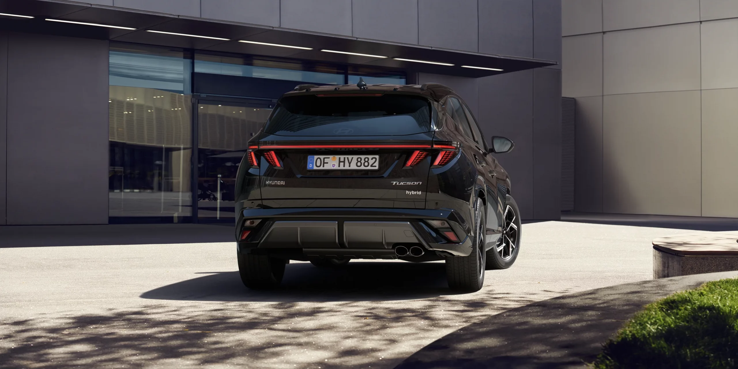 Black month 8 Schwarzer Hyundai SUV Hybrid von hinten vor modernem Gebäude und urbaner Umgebung geparkt