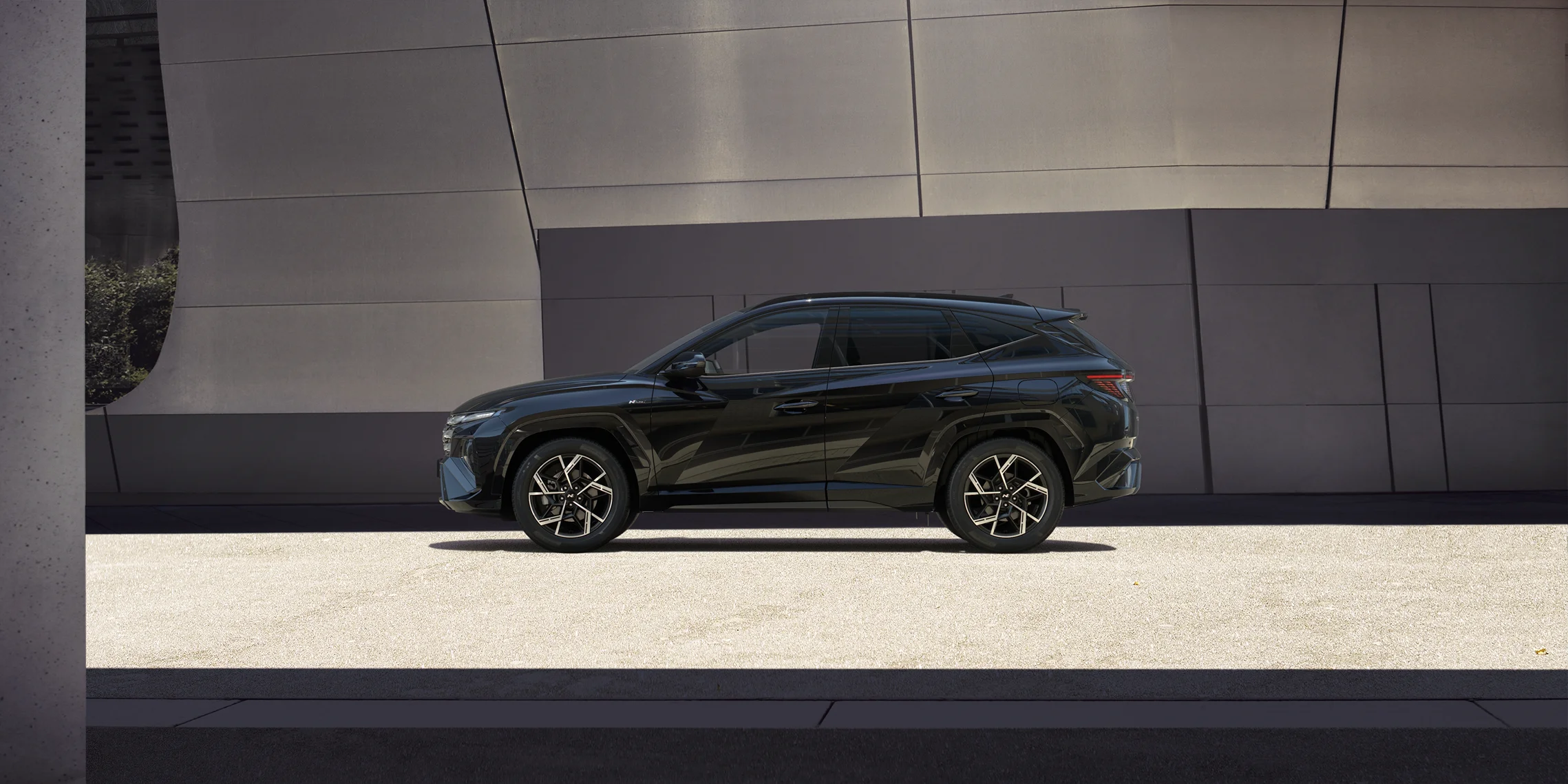 Black month 5 Schwarzer Hyundai SUV seitlich geparkt vor modernem Gebäude mit klaren Linien und Schattenspiel