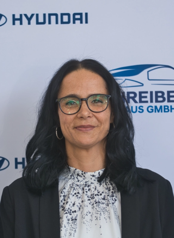 Business-Porträt einer Frau mit Brille vor Hyundai-Firmenwand, professionelle Bekleidung, freundlicher Ausdruck