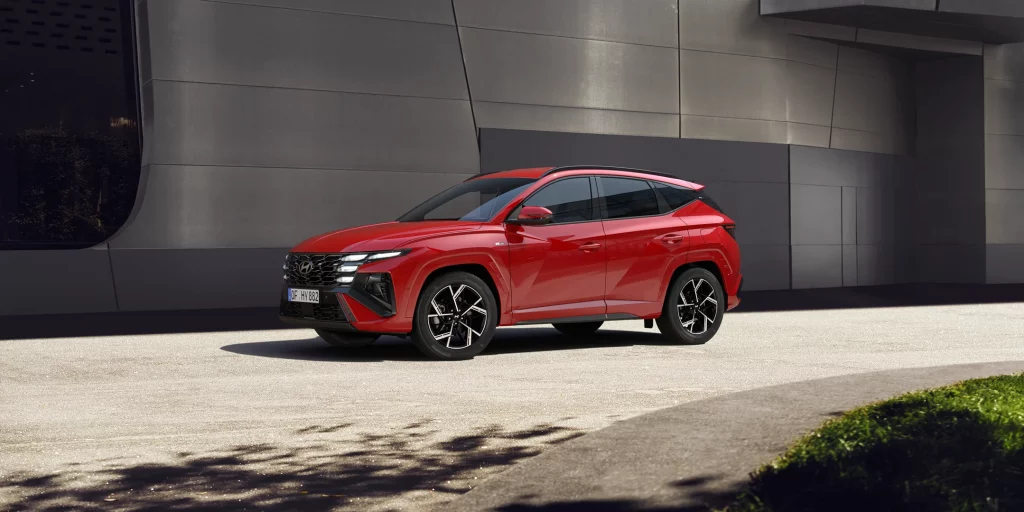 Roter moderner SUV seitlich vor grauem, urbanem Gebäude auf gepflasterter Straße geparkt