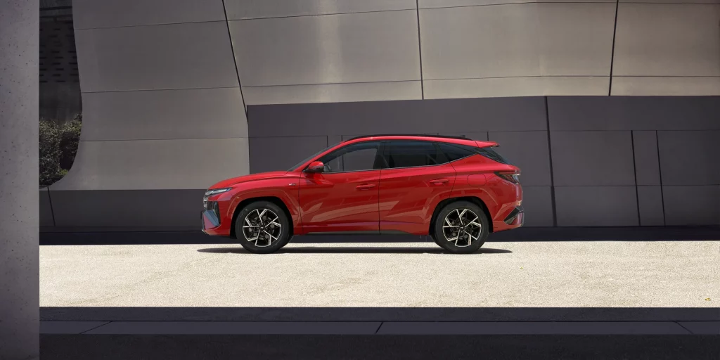 Roter SUV von der Seite vor moderner, grauer Architektur auf hell gepflastertem Boden geparkt