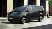 Schwarzer moderner Minivan in 3/4-Frontansicht vor zeitgenössischem Gebäude und urbaner Umgebung geparkt