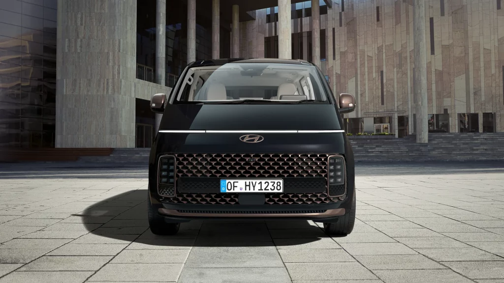 Schwarzer Hyundai Van frontal in urbanem Bereich vor moderner Architektur geparkt