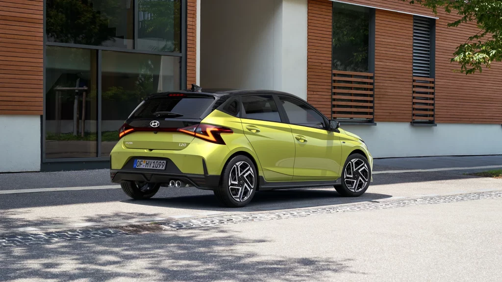 Grüner Hyundai Kompaktwagen von hinten in urbaner Umgebung vor modernem Gebäude geparkt