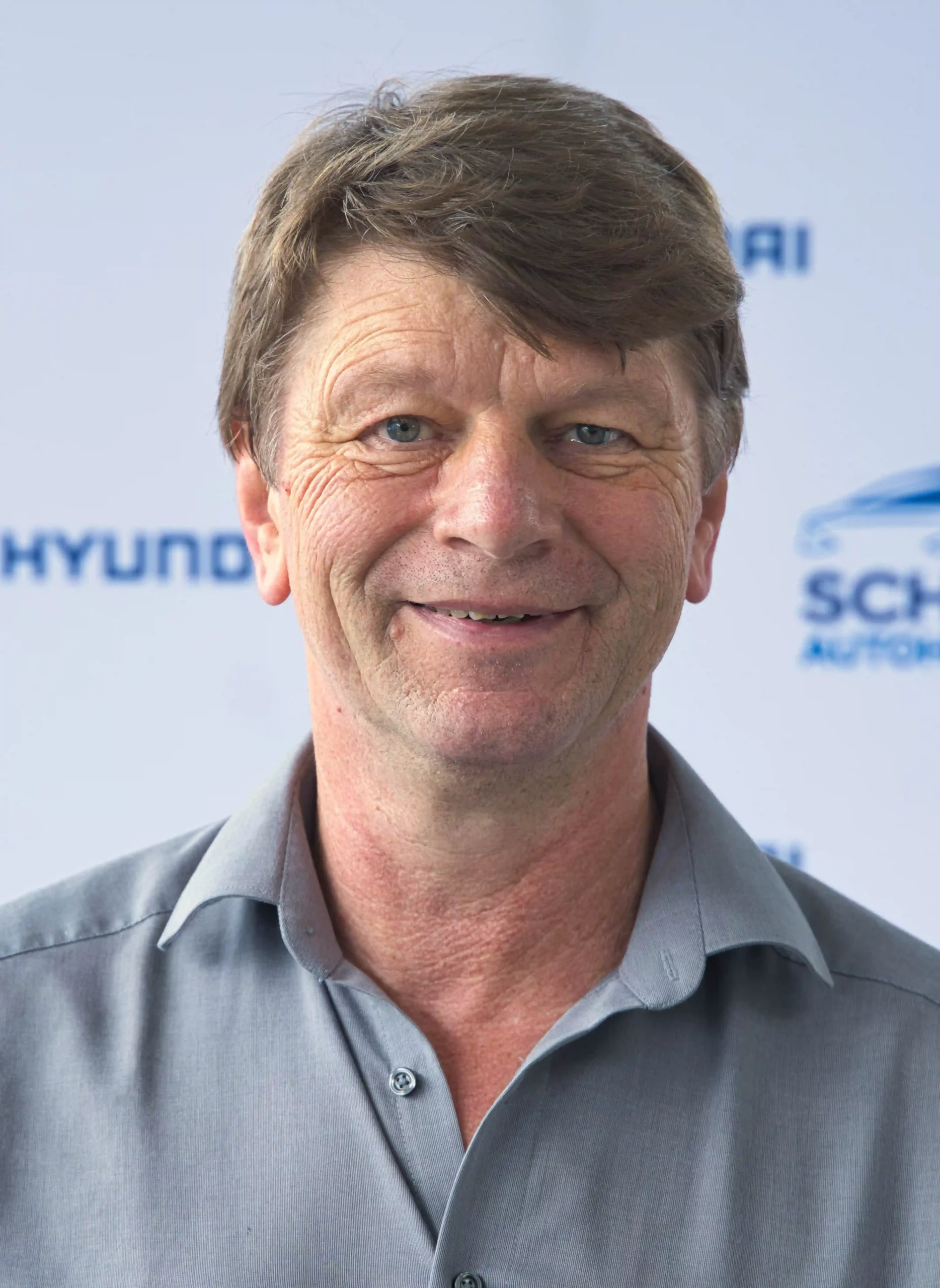 Porträt von Georg Sattler, lächelnder Mann vor neutralem Hintergrund – Autohaus Schreiber