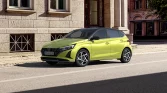 Gelbgrüner Hyundai Kompaktwagen, Drei‑Viertel‑Frontansicht, geparkt vor städtischer Steinfassade