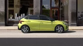 Limettengrüner Hyundai Kompaktwagen in Seitenansicht vor städtischem Schaufenster geparkt