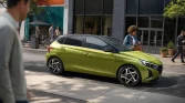 Leuchtend gelbgrüner Hyundai Kleinwagen, Seitenansicht, geparkt vor städtischer Ladenfront