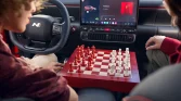 Schwarzer Hyundai Kompaktwagen Innenraum, Rücksitzperspektive, urban geparkt, zwei Personen mit Schachbrett.