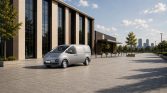 Silberner Hyundai Lieferwagen seitlich geparkt vor modernem Bürogebäude auf gepflastertem Vorplatz