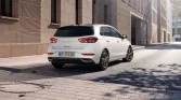 Weißer Hyundai Kompaktwagen, Heck-Drei-Viertel-Ansicht, geparkt an moderner Stadtfassade