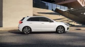 Weißer Hyundai Kompaktwagen Seitenansicht geparkt vor modernem Gebäude