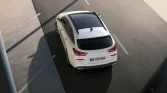 Weißer Hyundai Kombi, Draufsicht, geparkt auf Asphalt neben Beton, diagonaler Schatten