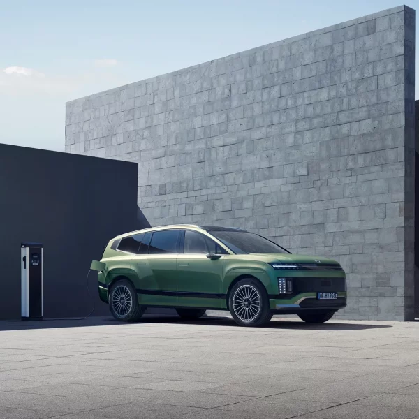 Grüner Hyundai Elektro-SUV seitlich geladen vor modernem, urbanem Gebäude mit klarer Himmelsperspektive